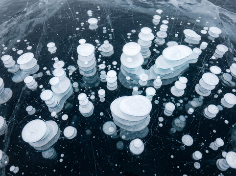 Close-up of methane bubbles trapped in frozen lake ice illustrating climate change and greenhouse gas emissions