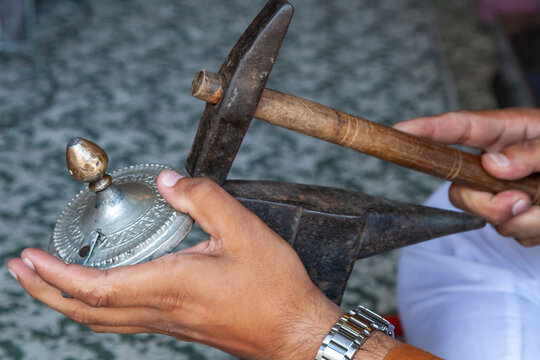 Close up of hands hammering an engraved metal lid on an anvil, Jammu and Kashmir, Srinagar, India