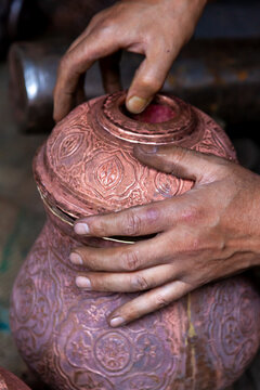 Hands of a craftsman holding an engraved copper pot, Jammu and Kashmir, Srinagar, India