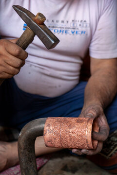 Coppersmith shaping an engraved copper sleeve with a hammer, Jammu and Kashmir, Srinagar, India