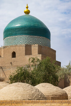 Khiva, Uzbekistan. The dome of the Pahlavon Mahmud Mausoleum, with ancient mud-brick tombs in the foreground