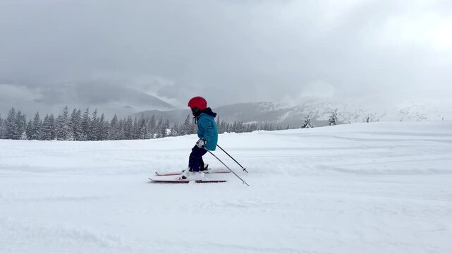 Active kid boy riding downhill,learn skiing in mountains alpine winter resort.little child enjoy extreme sport activities recreation,family luxury vacation