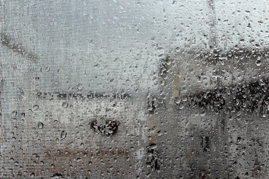 Photograph of glass covered with water droplets on a rainy day, creating reflections