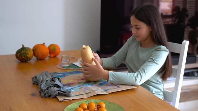 Young girl painting on a pumpking during fall season for Halloween event - Holiday, childhood and autumn lifestyle concept	