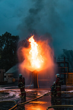 Firefighter rescue worker battling fire during disasters and accidents with courage beside burning industrial structure