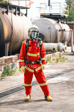 Firefighter rescue worker in protective gear confronting fire disasters and accidents with focus and readiness near industrial tank