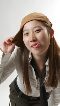 Playful Young Asian Woman Sticking Tongue Out Wearing Baseball Cap