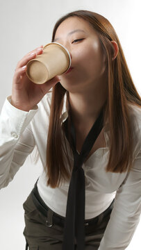 Young Asian Woman Drinking Coffee from Paper Cup in White Shirt and Tie