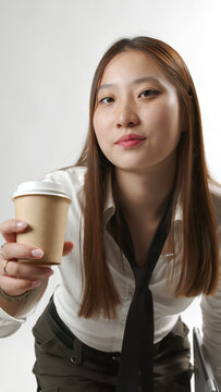 Young Asian Woman Offering Paper Coffee Cup in White Shirt and Tie