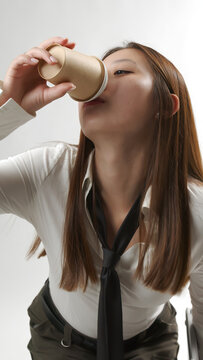 Young Asian Woman Drinking Coffee from Paper Cup in White Shirt and Tie