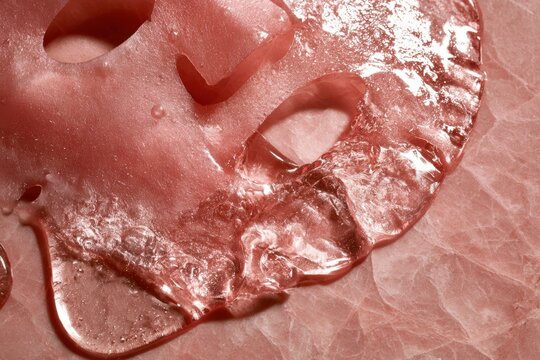 Pink hydrogel facial mask on a textured surface promoting skin hydration
