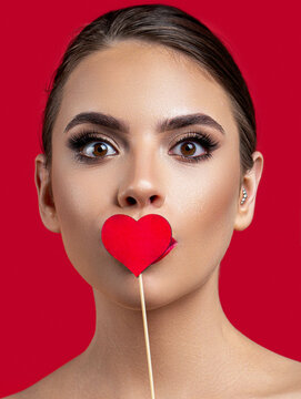 Portrait lovely coquettish cheerful girl holding in hand heart sending you kiss isolated red background