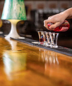 Red cocktail at the nightclub. Shot glasses with liquor in the bar, colored alcohol cocktails on a party, martini, vodka