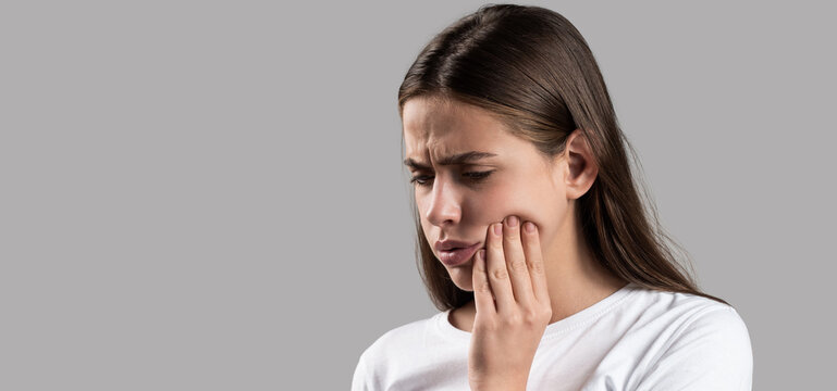 Toothache painkiller. Dental disease. Dental health and care concept. Girl suffer from toothache gray background