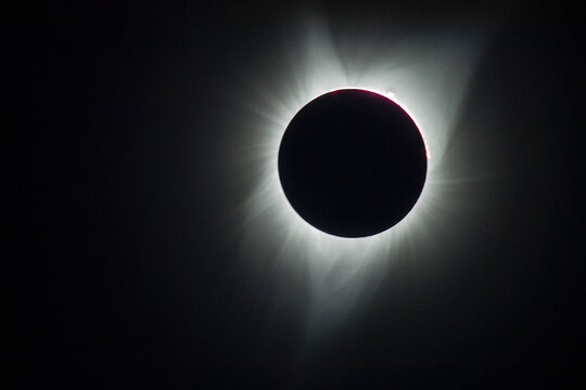 Solar eclipse with sun corona visible over dark sky