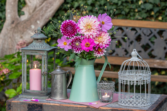 vintage Garten-Arrangement mit Blumenstrau&szlig; mit pink Dahlien, Schmuckk&ouml;rbchen und Zinnie, Laterne und Vogelk&auml;fig