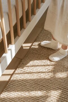 Woman wearing white socks beside wooden railing on textured woven rug indoors