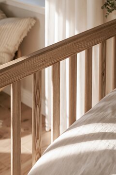 Closeup of light wood crib rail and vertical slats in sunlit nursery interior