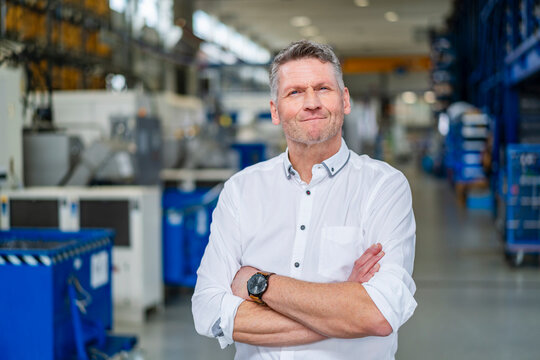 Confident manager in white shirt standing in factory production hall