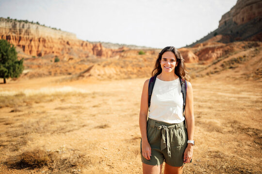 A smiling woman explores the desert canyon with a backpack