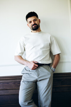 Young man standing indoors, confidently posing with a hand in his pocket, showcasing modern casual style