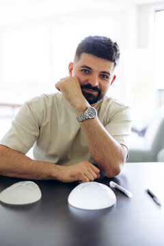 Male doctor sitting at a desk with silicone breast implants, consulting on cosmetic surgery procedures in a medical clinic