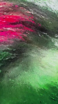 Red and green pigment strokes spread across a textured canvas during an abstract painting process