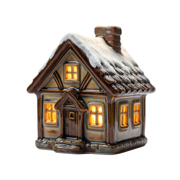 Glazed ceramic cottage with snowy roof and glowing windows, isolated on transparent background