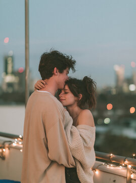 Romantic Young Couple Embracing on City Rooftop at Sunset