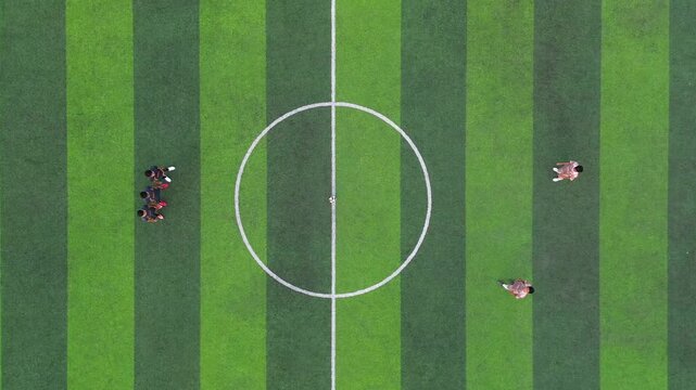 Aerial view of people playing a soccer match on a green field with striped patterns in East Lombok Regency, West Nusa Tenggara, Indonesia.
