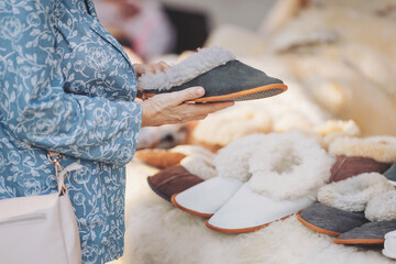 Browsing soft wool slippers at a cozy market stall on a bright daytime shopping trip © Cristina