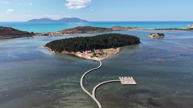 Aerial view of Zvernec Monastery on the island surrounded by the Narta Lagoon with a wooden footbridge leading to the shore in Zvernec, Vlore County, Albania.