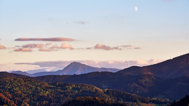 Timelapse of autumn mountain landscape with moon during twilight