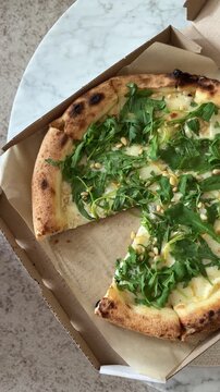Woman taking pizza piece with cheese and arugula in paper box top view close up. Fast food snacks.