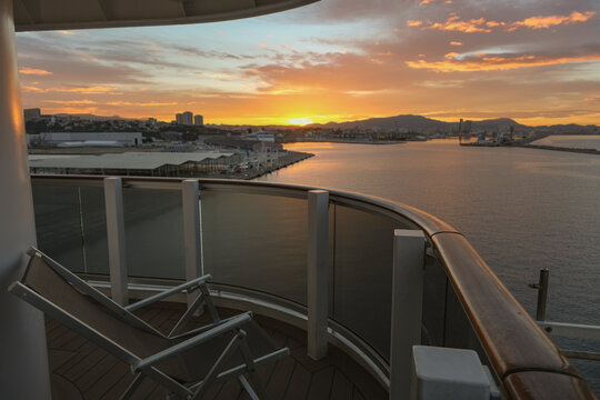 Pooldeck or swimmingpool with sun deck on modern cruiseship cruise ship liner in port with sun loungers ready for cruising to Mediterranean on sunny day with city skyline in background