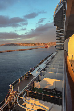 Pooldeck or swimmingpool with sun deck on modern cruiseship cruise ship liner in port with sun loungers ready for cruising to Mediterranean on sunny day with city skyline in background