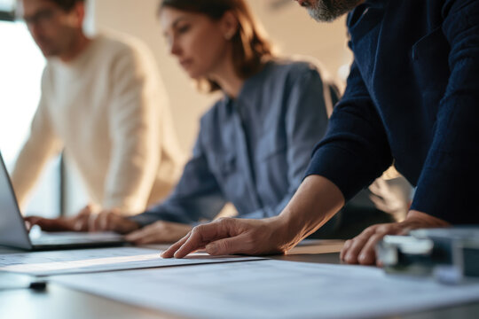 A group of professionals is engaged in a creative brainstorming session, examining plans and ideas to drive innovative solutions and enhance project outcomes effectively.