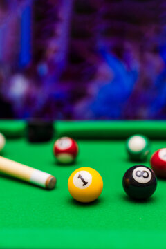 Pool table with billiard balls and cue in pub or lounge room with vertical copy space.