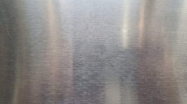 A close-up background featuring a brushed, shimmering blue-grey metallic texture, along with horizontally polished stainless steel and fine scratch marks on the surface&mdash;resulting in a finish that appe