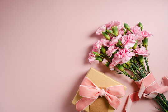 Pink carnations and gift box with velvet ribbon flat lay with copy space