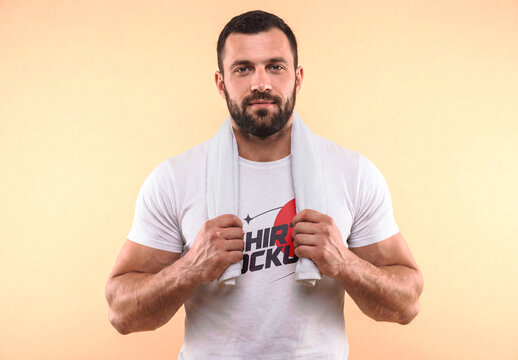 Muscular Man Wearing White T-Shirt Mockup with Gym Towel on Peach Background