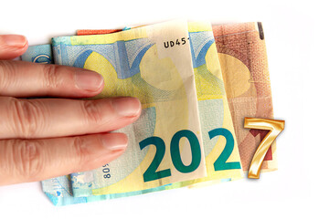 2027 written with euros bank notes in a hand isolated on white background, new year greetings money concept © Delphotostock