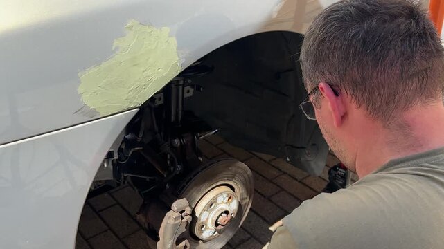 Mechanic replacing a suspension strut with hand tools. Automotive repair, DIY vehicle maintenance, shock absorber replacement, brake service and professional garage work.