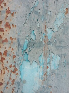 Peeling blue paint on rusty metal wall with corrosion texture, grunge vintage industrial background