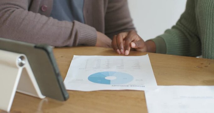 Right person is placing sheet at wooden table, tracing pie chart and tapping rows for review