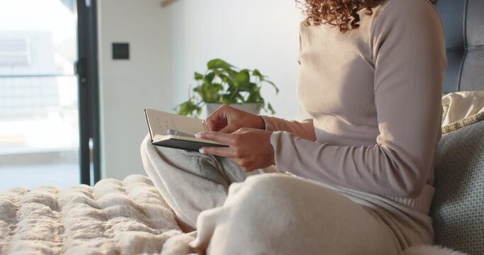 Woman is finishing pages closing book placing it left laptop visible sitting upright to meditate