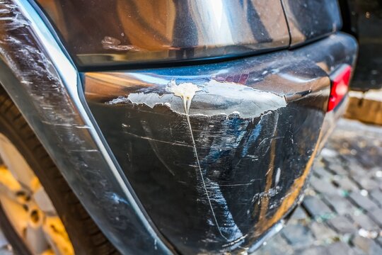 Damaged black car bumper with peeling paint and scratches