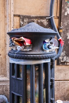 Overflowing public trash can on a street in Rome Italy