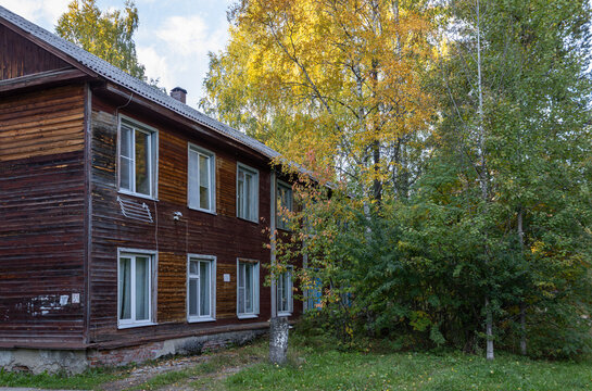 The facade of two-story wooden residential house surrounded by colorful autumn nature in a provincial town of Russia.