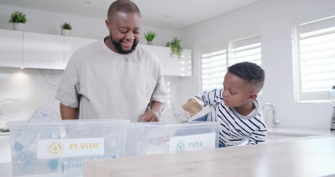 African American dad placing PLASTIC,PAPER bins, guiding boys sorting bottles in kitchen to recycle